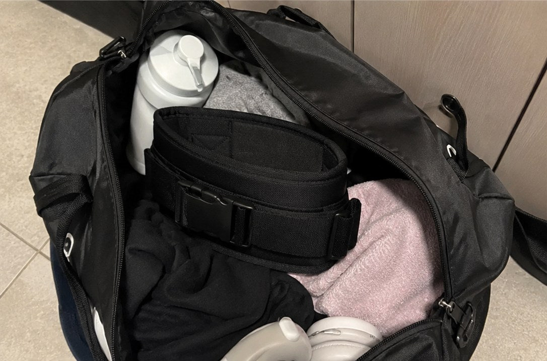 Ceinture Ergolift noire rangée dans un sac de sport avec des accessoires